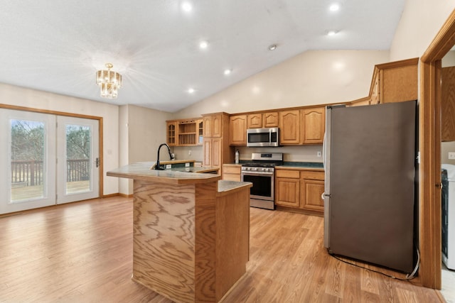 kitchen with pendant lighting, a kitchen island with sink, an inviting chandelier, light hardwood / wood-style flooring, and stainless steel appliances