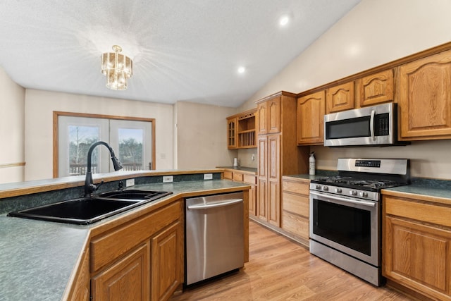 kitchen featuring appliances with stainless steel finishes, sink, light hardwood / wood-style flooring, a chandelier, and lofted ceiling