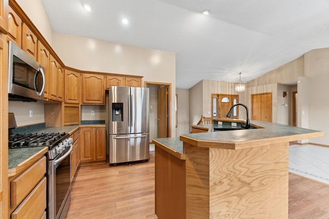 kitchen featuring a kitchen island with sink, sink, light wood-type flooring, appliances with stainless steel finishes, and a notable chandelier