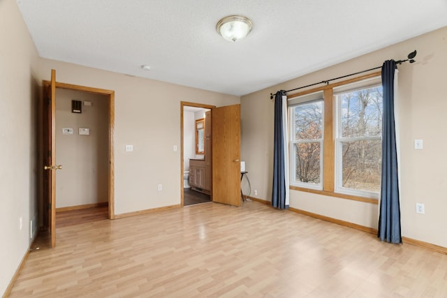 spare room with a textured ceiling and light wood-type flooring