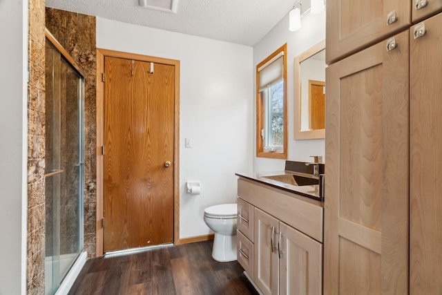 bathroom featuring vanity, a shower with door, toilet, a textured ceiling, and wood-type flooring