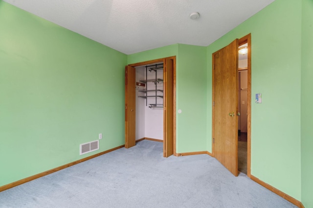 unfurnished bedroom featuring a closet, light colored carpet, and a textured ceiling