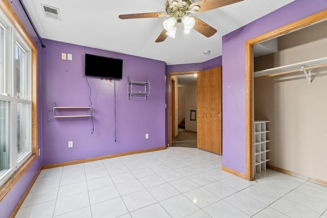 unfurnished bedroom featuring ceiling fan, light tile patterned floors, multiple windows, and a closet