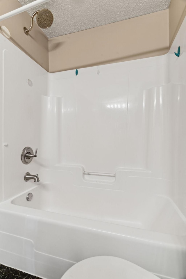 bathroom featuring tub / shower combination, a textured ceiling, and toilet