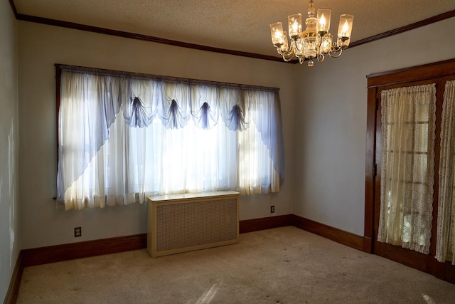 carpeted empty room featuring a textured ceiling, baseboards, a notable chandelier, and crown molding