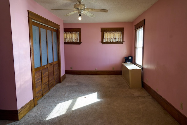 carpeted bedroom with a closet, ceiling fan, a textured ceiling, and baseboards