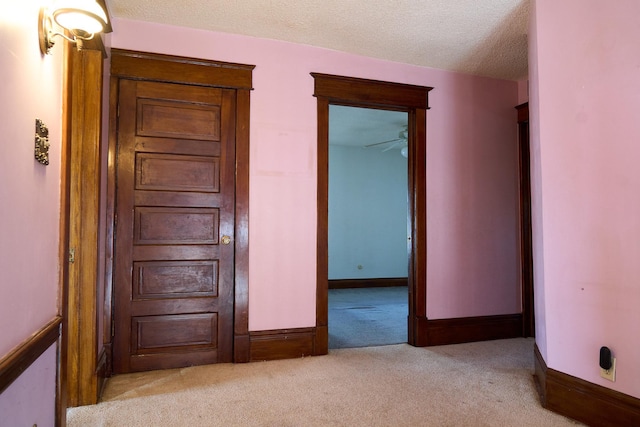 unfurnished bedroom featuring light carpet, a textured ceiling, and baseboards