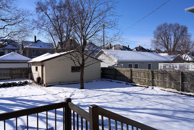 snowy yard featuring an outdoor structure and a fenced backyard