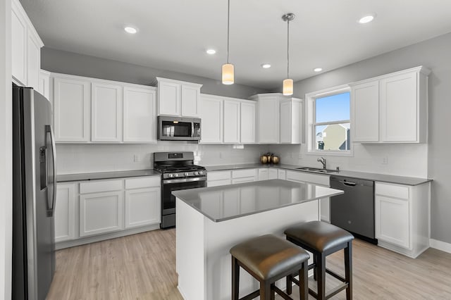 kitchen featuring a center island, sink, stainless steel appliances, and white cabinetry