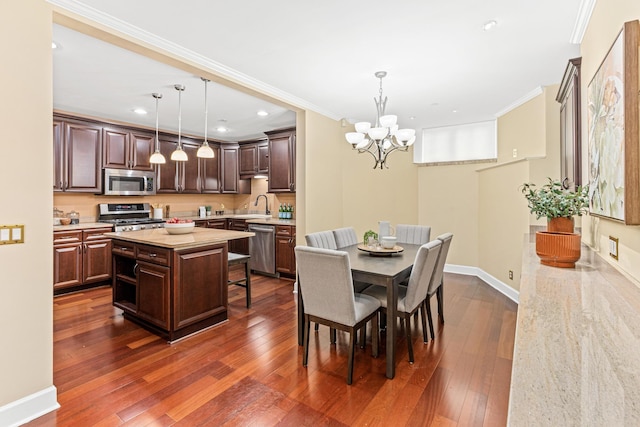 dining area with sink, dark wood-type flooring, a notable chandelier, and ornamental molding