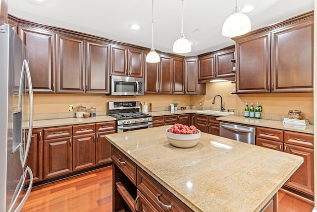 kitchen featuring light hardwood / wood-style floors, hanging light fixtures, stainless steel appliances, and sink