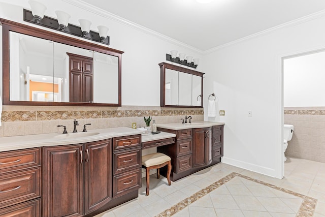 bathroom featuring tile patterned floors, crown molding, toilet, vanity, and tile walls