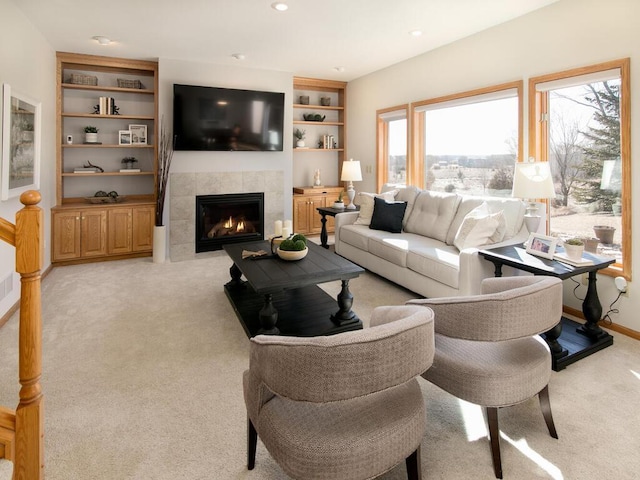 carpeted living room featuring a tiled fireplace and built in features