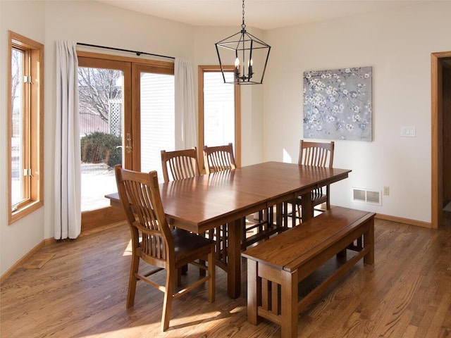 dining room with dark wood-type flooring, french doors, and a chandelier