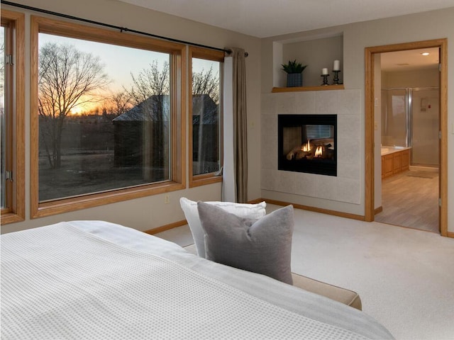 carpeted bedroom featuring ensuite bathroom and a tile fireplace