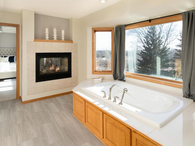 bathroom featuring a tiled fireplace and a bathing tub