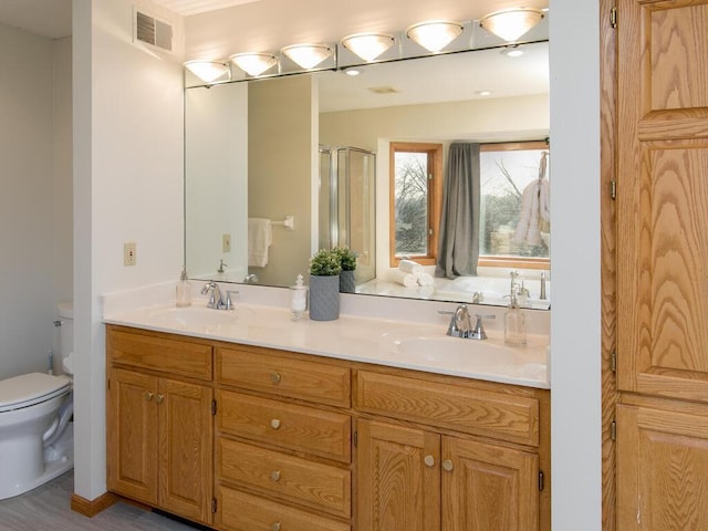 bathroom featuring vanity, a shower with shower door, and toilet