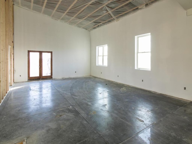 unfurnished room featuring a towering ceiling and french doors