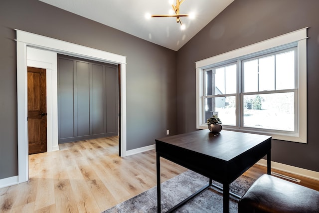 office space featuring vaulted ceiling, baseboards, light wood-style flooring, and a chandelier