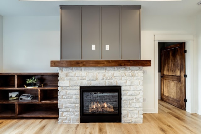 detailed view of wood finished floors, a warm lit fireplace, and baseboards