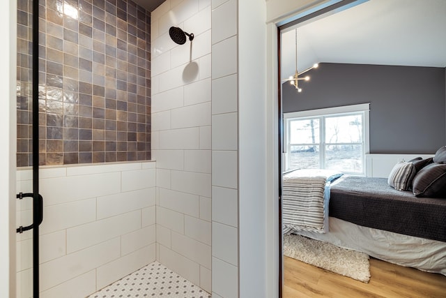 ensuite bathroom featuring a stall shower, a chandelier, wood finished floors, and lofted ceiling