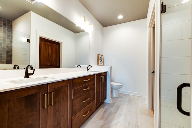 bathroom with toilet, double vanity, a tile shower, baseboards, and recessed lighting