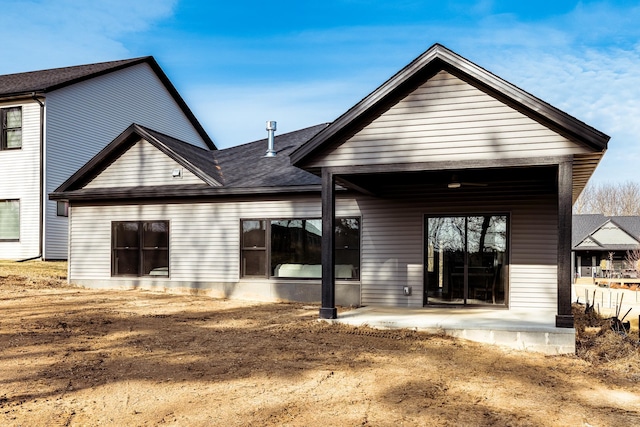 rear view of property featuring a patio and a shingled roof