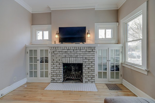 unfurnished living room with a healthy amount of sunlight, a brick fireplace, crown molding, and light hardwood / wood-style flooring