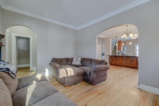 living room with crown molding, an inviting chandelier, and light hardwood / wood-style floors