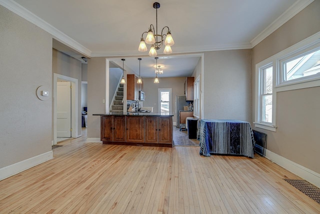 kitchen featuring light hardwood / wood-style floors, crown molding, an inviting chandelier, hanging light fixtures, and appliances with stainless steel finishes