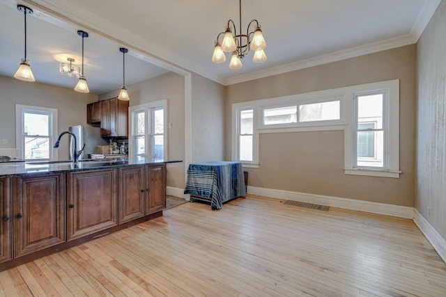 kitchen with a notable chandelier, light hardwood / wood-style floors, sink, hanging light fixtures, and plenty of natural light