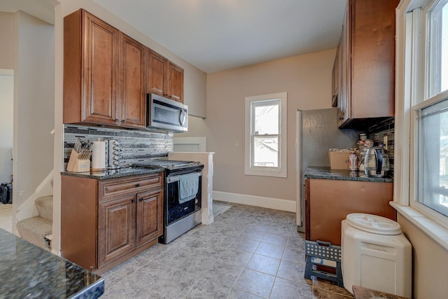 kitchen with decorative backsplash, dark stone counters, and stainless steel appliances