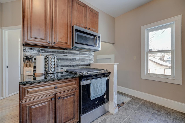 kitchen with appliances with stainless steel finishes, backsplash, and dark stone counters