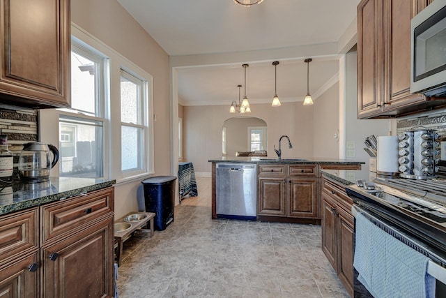 kitchen featuring stainless steel appliances, dark stone countertops, sink, hanging light fixtures, and ornamental molding