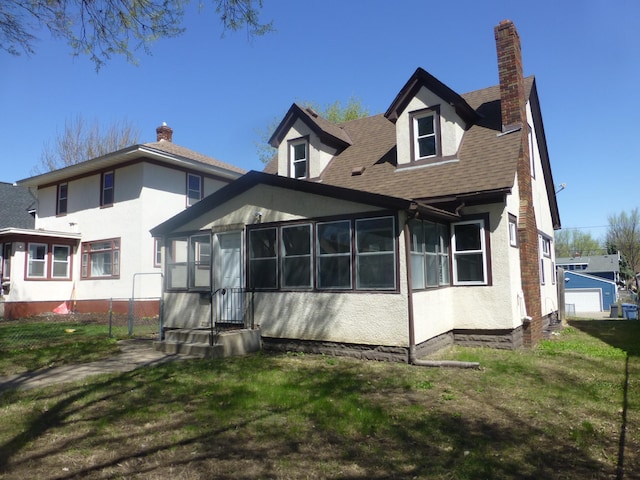 back of property featuring a sunroom, a lawn, roof with shingles, and a chimney