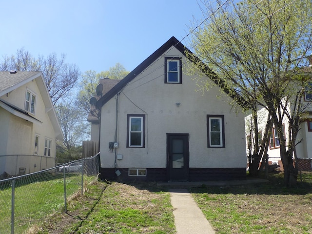 rear view of property with fence, stucco siding, and a yard