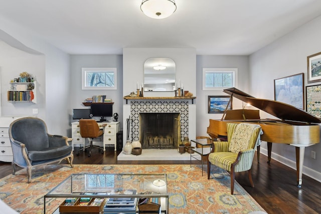 living room featuring a tiled fireplace and dark hardwood / wood-style floors