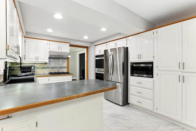 8385 Pleasant View Dr, Mounds View, MN 55112 - kitchen with appliances with stainless steel finishes, a peninsula, light marble finish flooring, under cabinet range hood, and decorative backsplash
