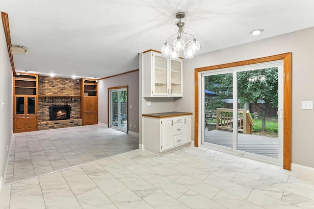 8385 Pleasant View Dr, Mounds View, MN 55112 - kitchen featuring white cabinets, a brick fireplace, glass insert cabinets, decorative light fixtures, and a textured ceiling