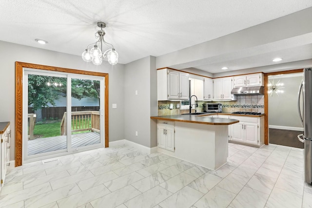 8385 Pleasant View Dr, Mounds View, MN 55112 - kitchen with under cabinet range hood, a peninsula, light marble finish floors, a chandelier, and tasteful backsplash