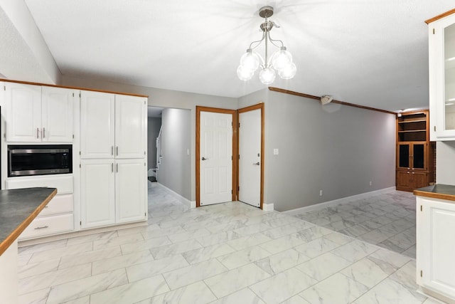 8385 Pleasant View Dr, Mounds View, MN 55112 - kitchen with stainless steel microwave, white cabinetry, dark countertops, a chandelier, and glass insert cabinets