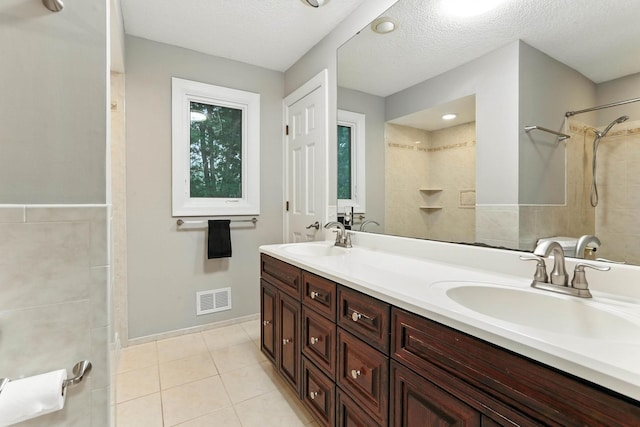 8385 Pleasant View Dr, Mounds View, MN 55112 - bathroom featuring double vanity, tile patterned floors, a tile shower, and a textured ceiling