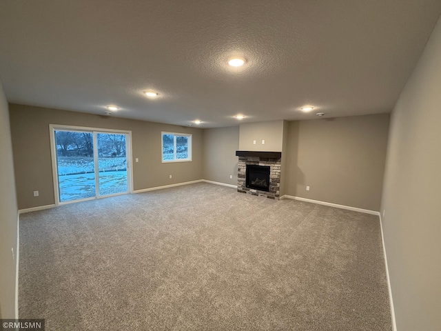 unfurnished living room featuring a textured ceiling, carpet floors, and a stone fireplace