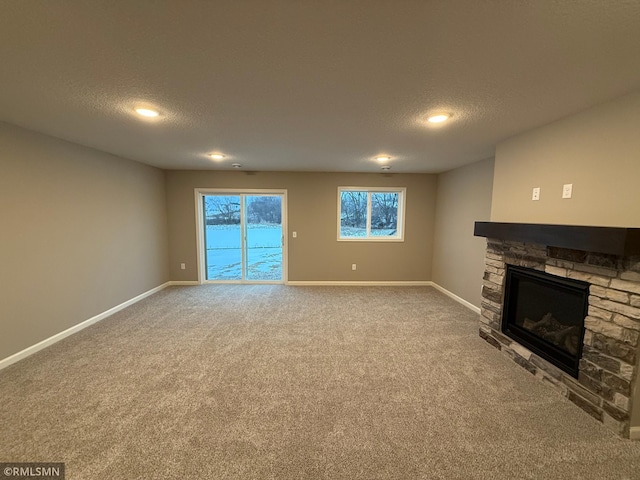 unfurnished living room featuring a fireplace, carpet floors, and a textured ceiling