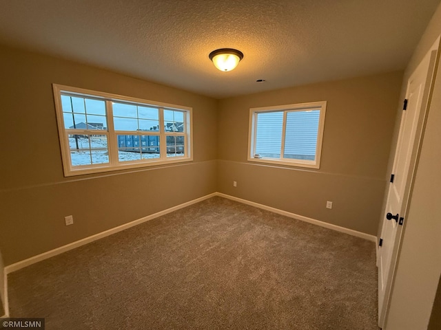 carpeted empty room featuring a water view, a wealth of natural light, and a textured ceiling