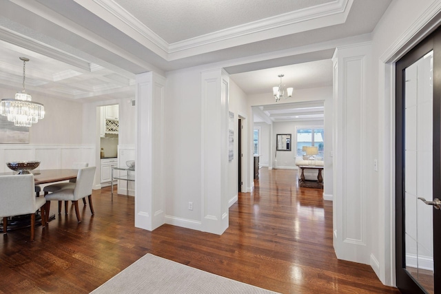 hallway with ornamental molding, dark wood-type flooring, and an inviting chandelier