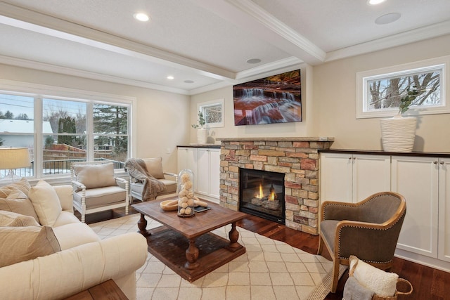 living room featuring beamed ceiling, a fireplace, light wood-type flooring, and crown molding