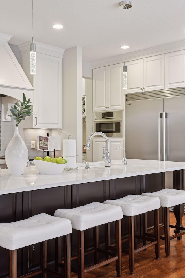 kitchen featuring pendant lighting, dark wood-type flooring, white cabinets, appliances with stainless steel finishes, and light stone counters