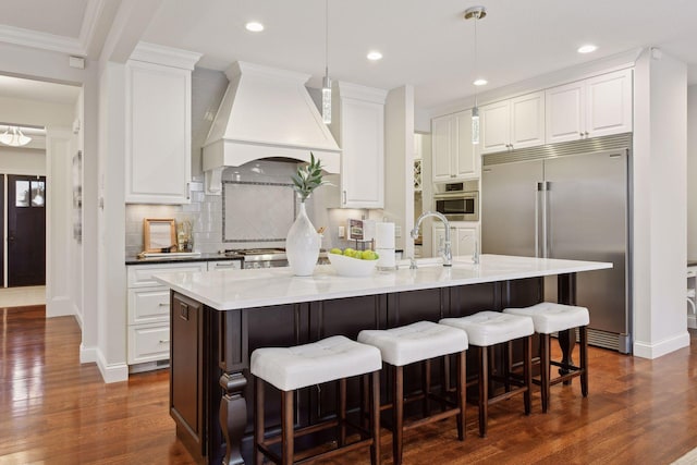 kitchen featuring pendant lighting, white cabinets, premium range hood, and stainless steel appliances