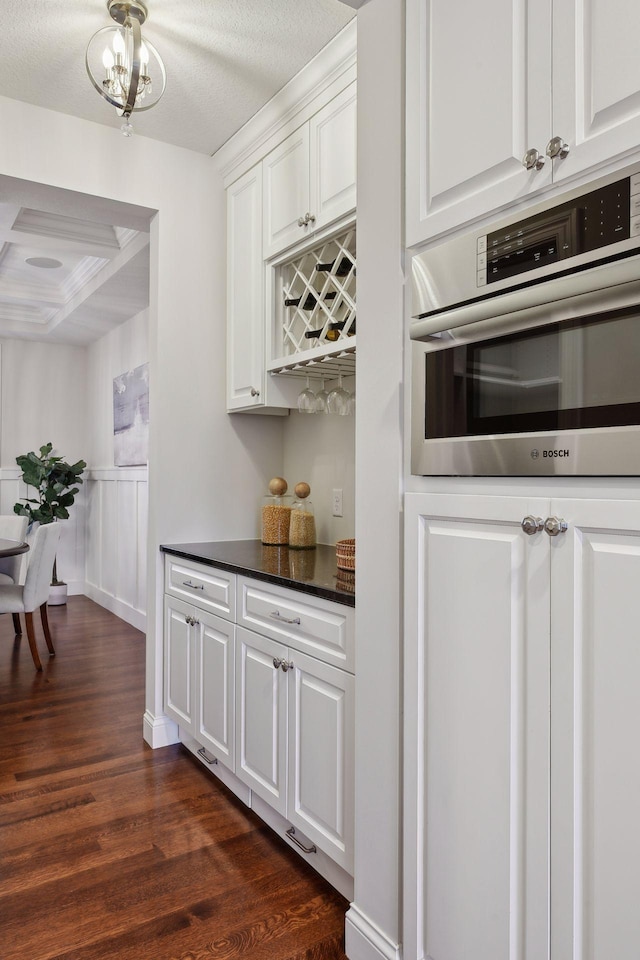 kitchen featuring stainless steel oven, dark wood-type flooring, coffered ceiling, white cabinets, and beamed ceiling